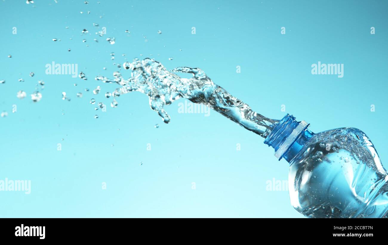 Exploding fresh water from plastic bottle on soft blue background. Free