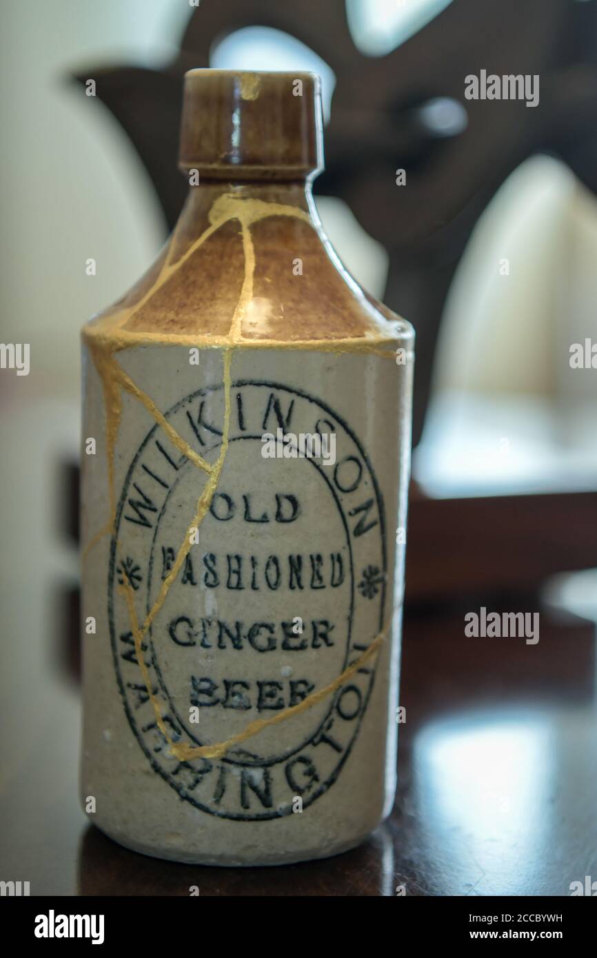 Kintsugi gold epoxy repair to broken stoneware ginger beer bottle Stock Photo