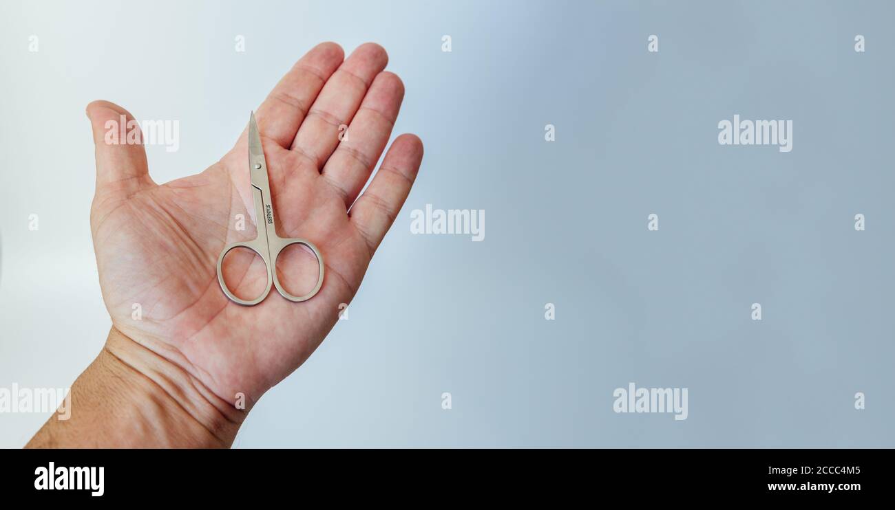 Man's open hand with a small manicure scissors in his palm, isolated on white background. copy space Stock Photo