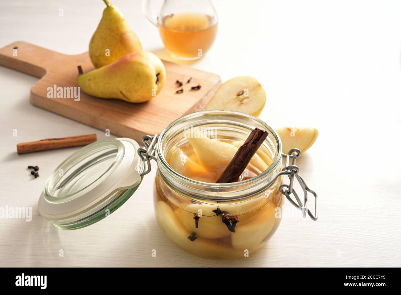 Preserving pears after harvest with cinnamon and cloves in a glass jar to have canned summer fruits also in winter, white painted table, copy space, s Stock Photo