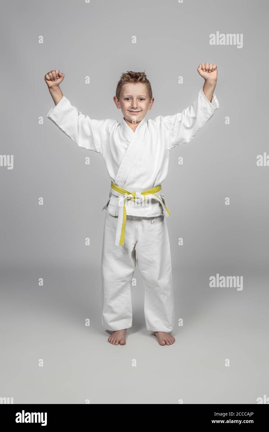 portrait of a child wearing martial arts kimono standing smiling and in a winning stance. Stock Photo