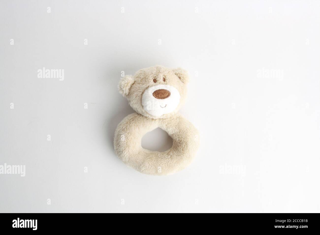 Top view of a cute teddy bear rattle on a white surface under the ...