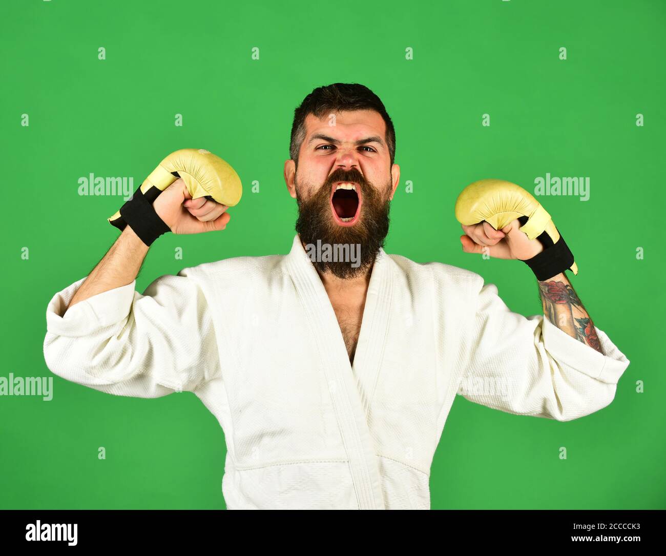 Man with beard in white kimono on green background. Karate man with