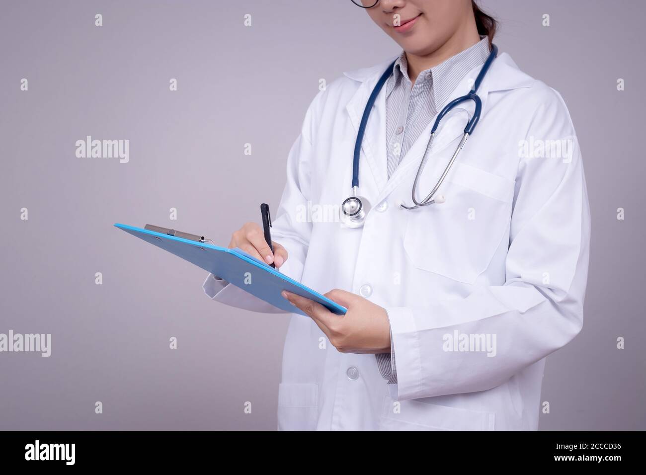 Healthy concept : Young Asian doctor writing on clipboard  for patient chart , anonymous face. Beautiful Asia female model in her 30s Stock Photo
