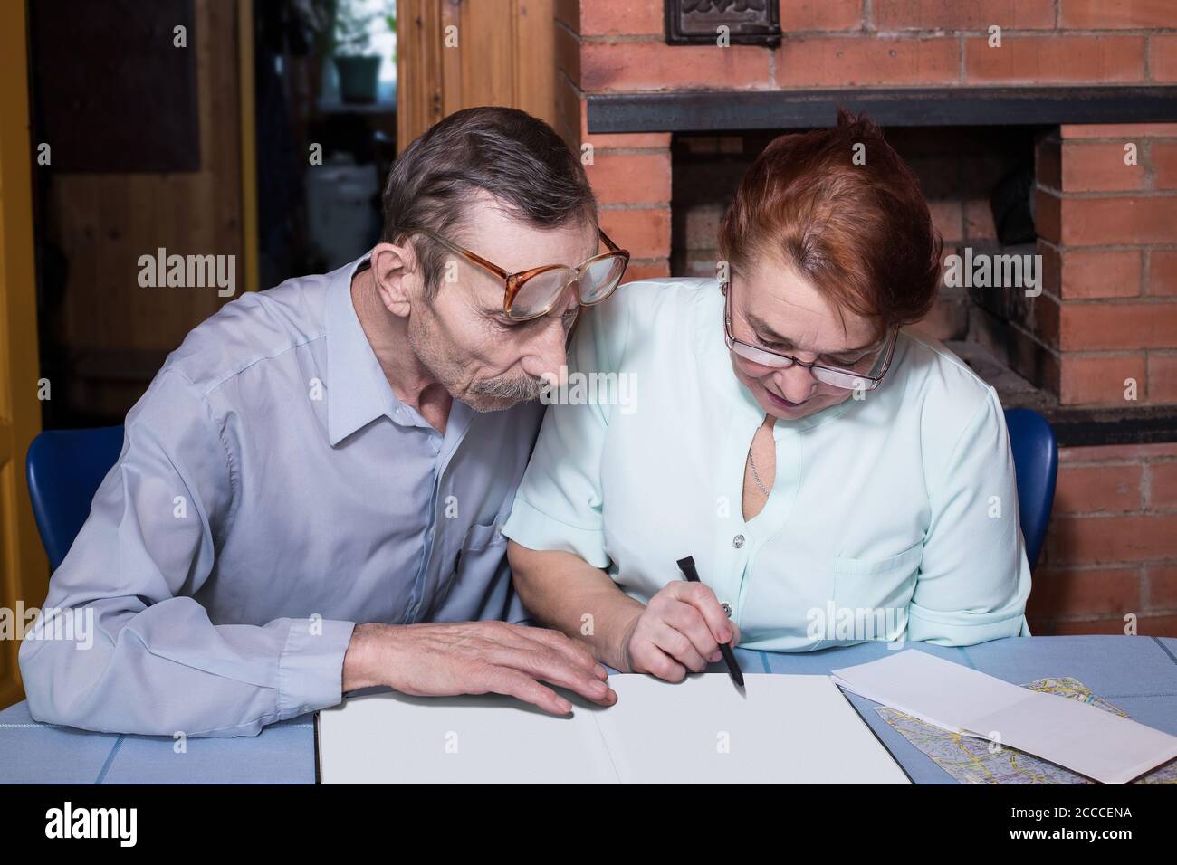 Senior couple in the country house discuss something, album with blank pages, copy space Stock Photo