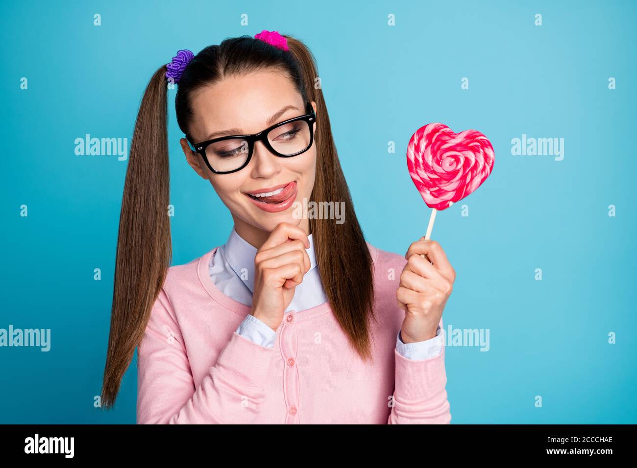 Close-up portrait of her she nice attractive pretty girlish funky cheerful cheery college girl holding in hand candy licking lip isolated over bright Stock Photo