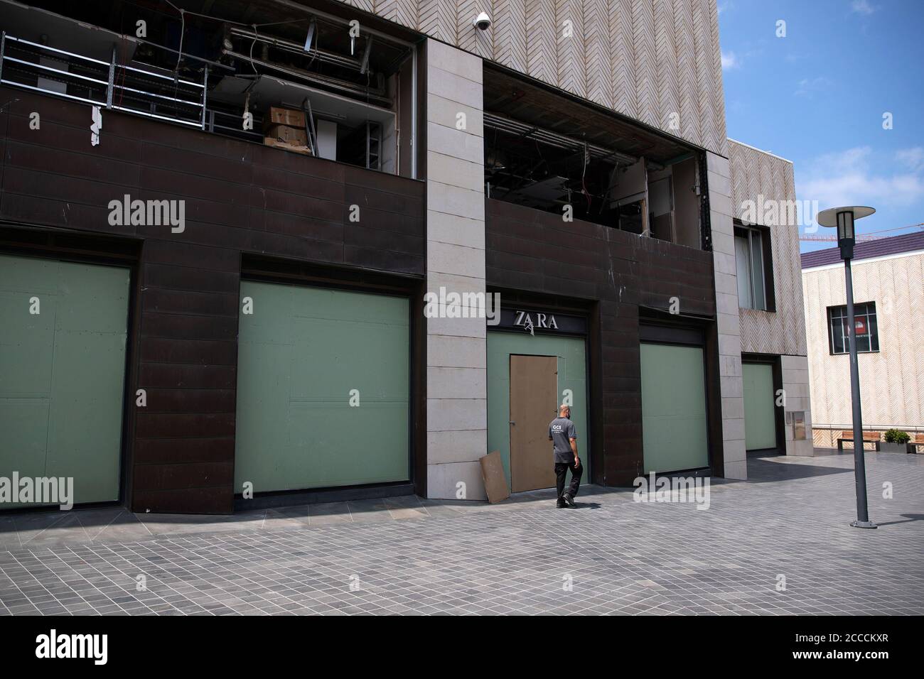 A man walks past a closed Zara shop, which was damaged from a massive  explosion at Beirut port, as Lebanon imposed a partial lockdown for two  weeks starting on Friday in an