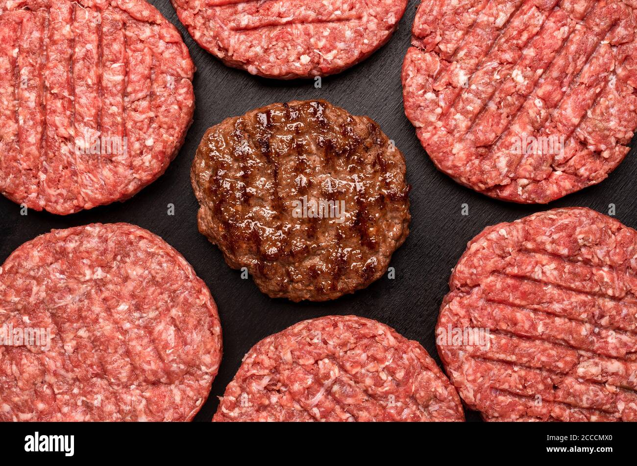 Above view with burger beef patties isolated on a black table. Flat lay  with cooked and uncooked burger patties. Hamburger beef patty grilled, top  vie Stock Photo - Alamy