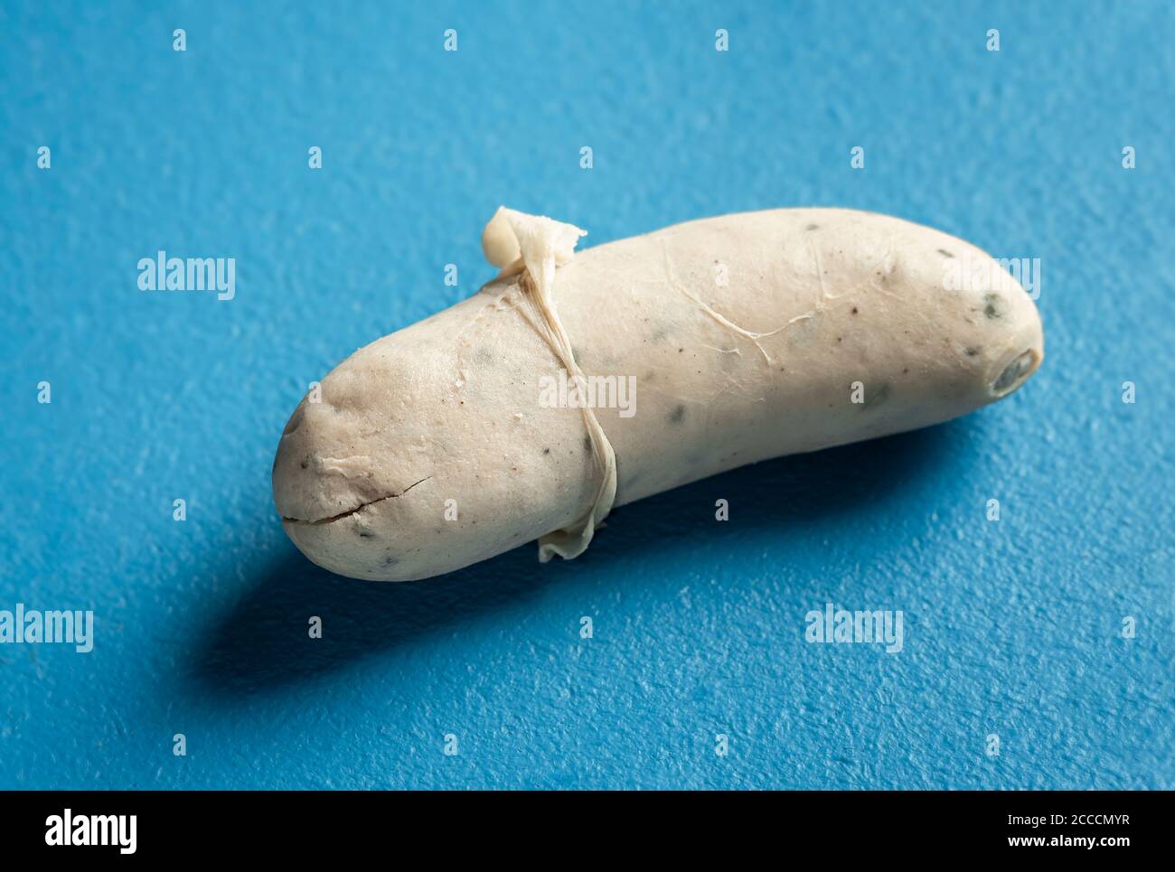 White sausage close-up with the skin peeled off, isolated on a blue background. Bavarian veal sausage. Traditional German food. Hot to eat weisswurst. Stock Photo