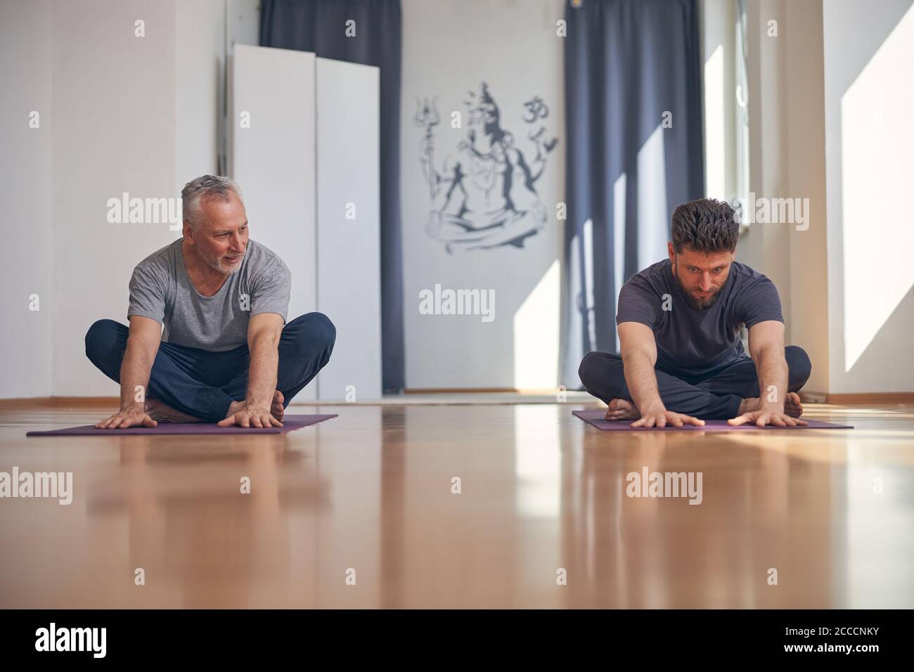 Two yogis doing a forward bend exercise Stock Photo
