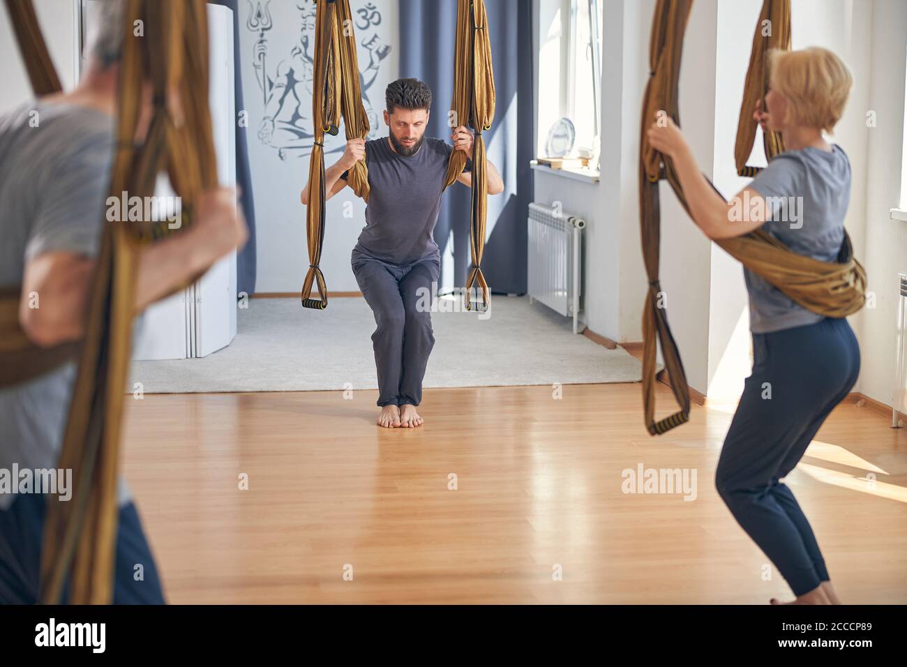 Three people using hammocks at the aerial yoga class Stock Photo Alamy