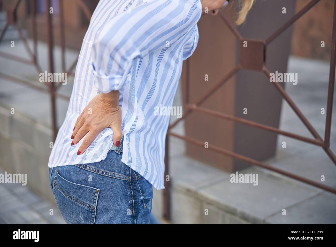 Woman with a lower back pain leaning on the railing Stock Photo Alamy