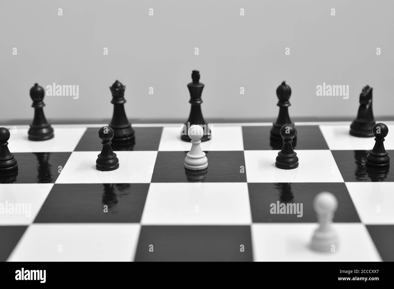 image shows a white pawn standing up to a black king. Image symbolizes bravery and sacrifice as the white pawn will likely be killed in the next move. Stock Photo