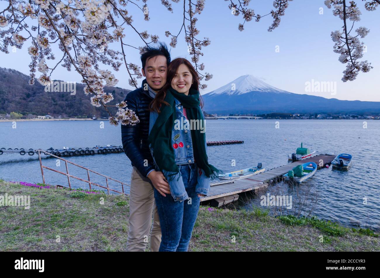 Lovely couple taking photo at Kawaguchiko with Fuji mountain and cherry blossoms view in spring, Japan. Stock Photo