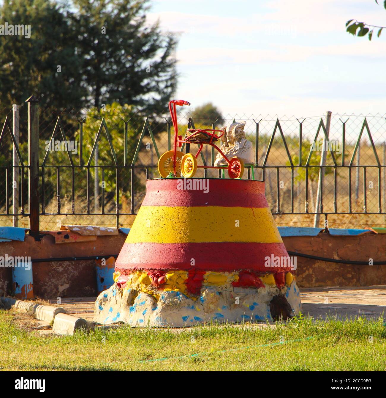 Old tricycle mounted on top of concrete cone in a garden patriotically