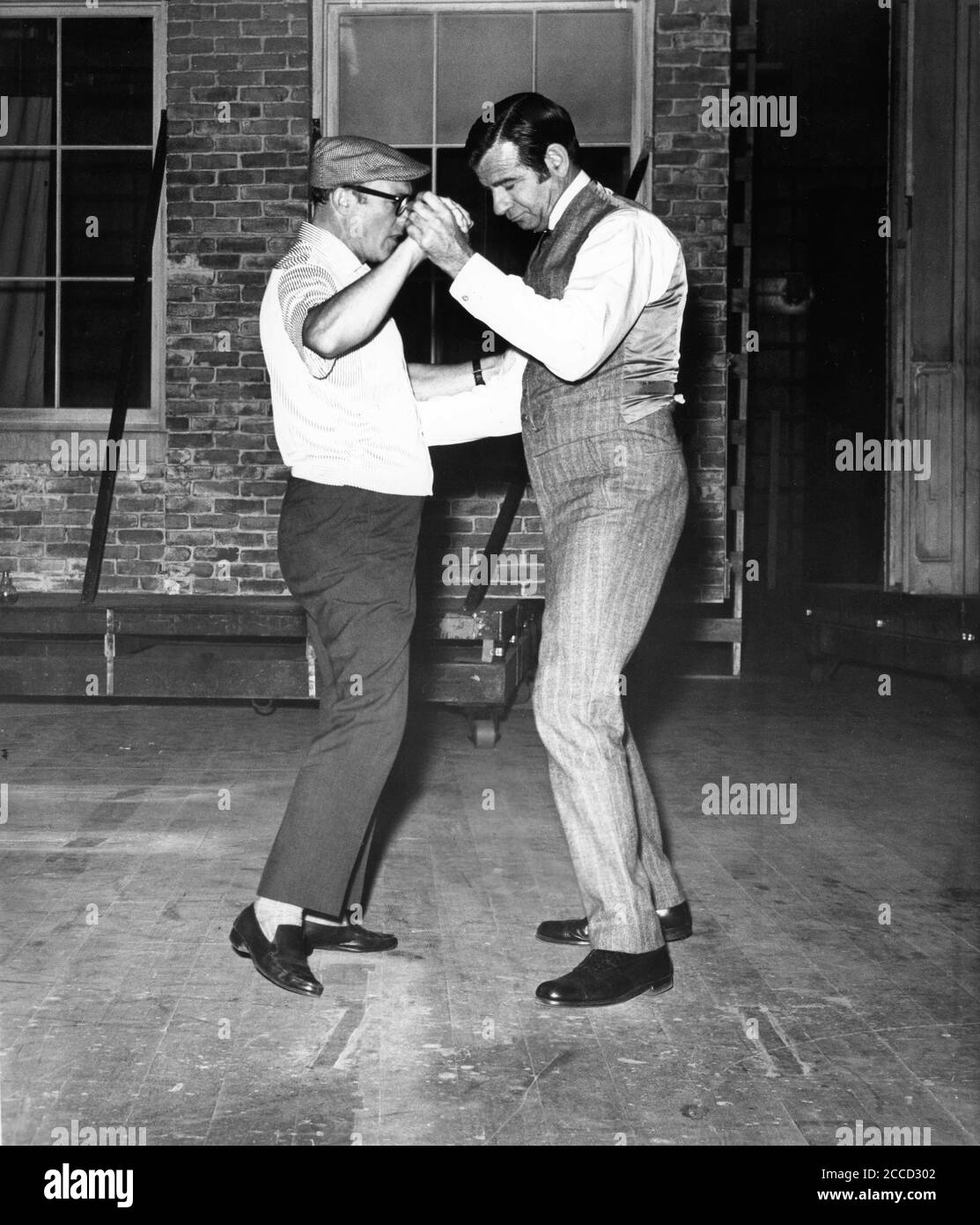 GENE KELLY and WALTER MATTHAU on set candid dancing practice during filming of HELLO , DOLLY ! 1969 director GENE KELLY music and lyrics Jerry Herman Chenault Productions / Twentieth Century Fox Stock Photo