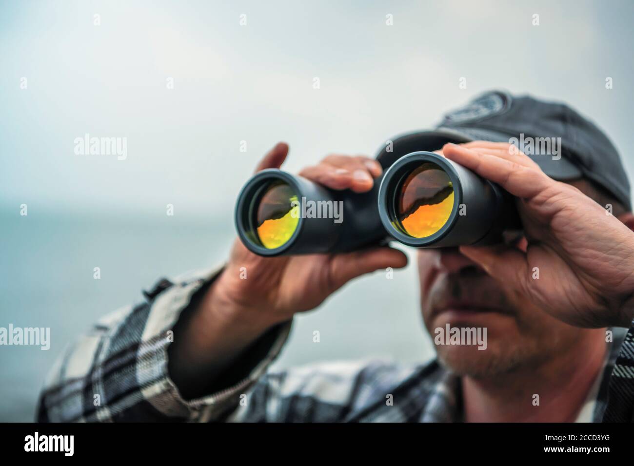 Close up shot of man looking through binoculars with not visible face. Stock Photo