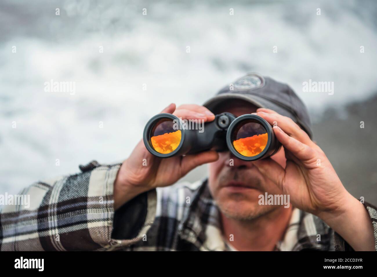 Close up shot of man looking through binoculars with not visible face. Stock Photo