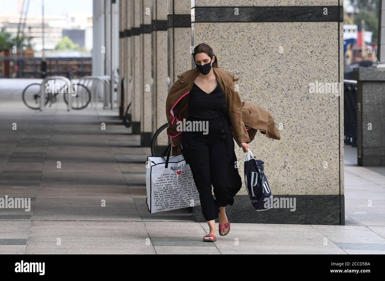 A woman walking in the wind at Canary Wharf, London. Strong winds are expected to sweep across the UK ahead of the weekend, bringing the potential for travel disruption and flooding. Stock Photo