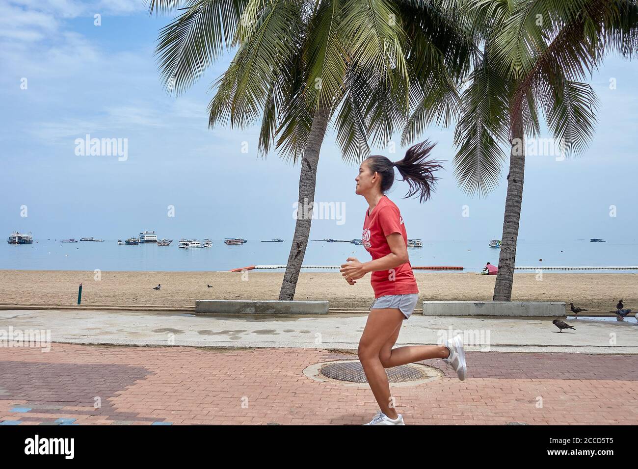 Woman running alongside the beach,  female keep fit exercise. People exercising. Thailand Southeast Asia Stock Photo
