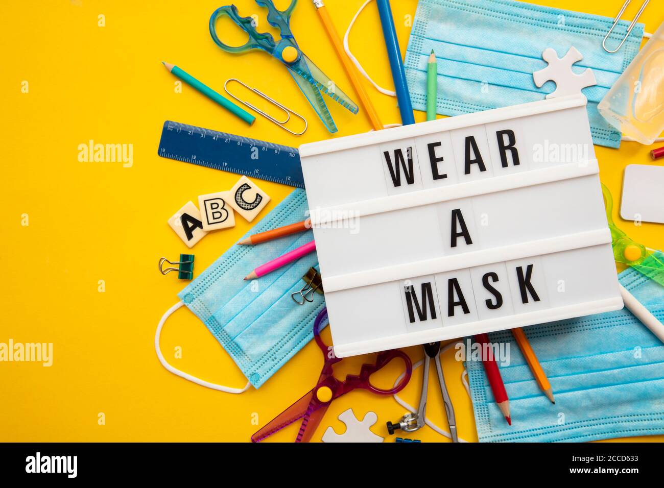 Wear a mask lightbox message with school equipment and covid masks Stock Photo