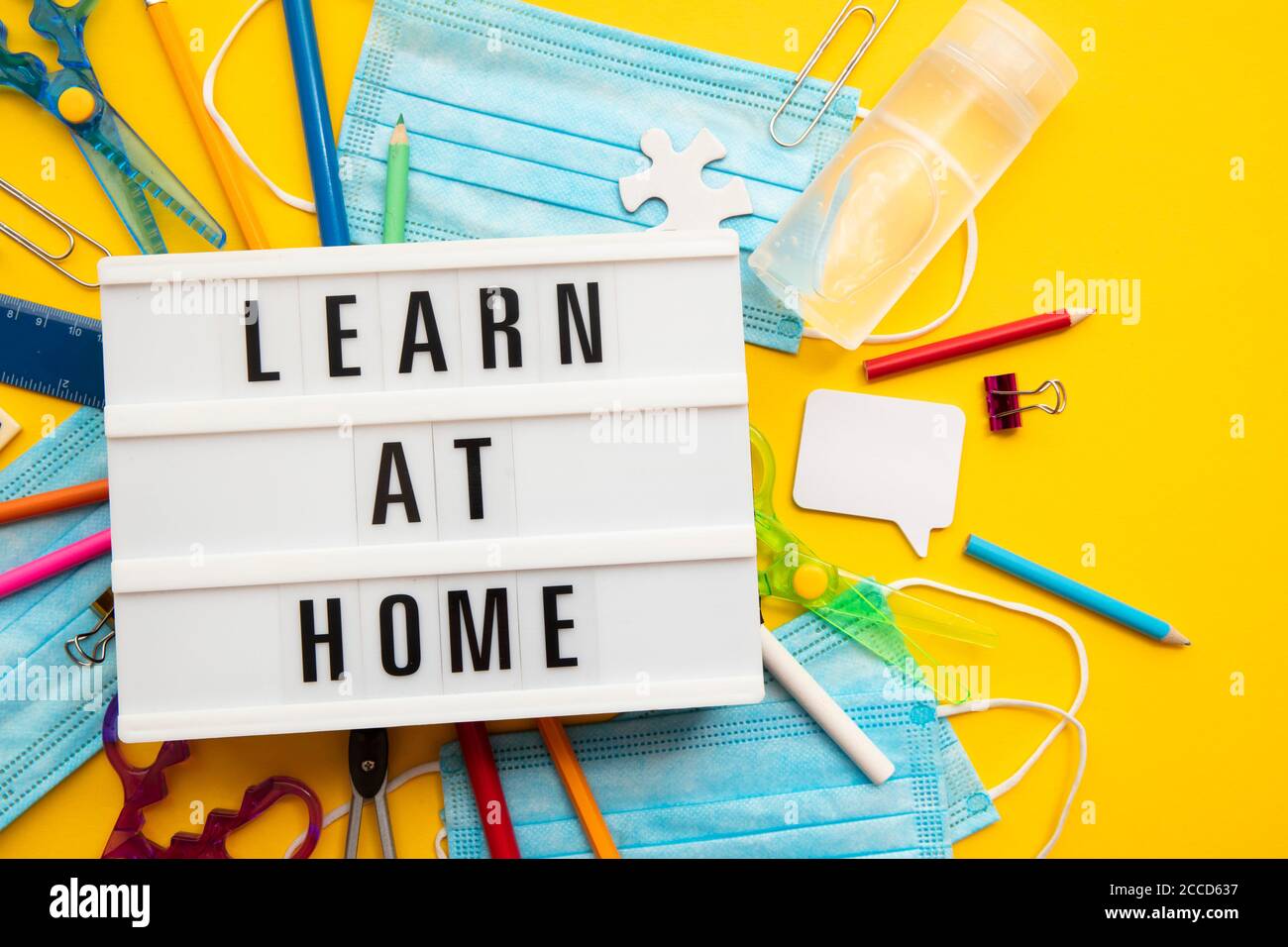 Learn at home lightbox message with school equipment and covid masks Stock Photo