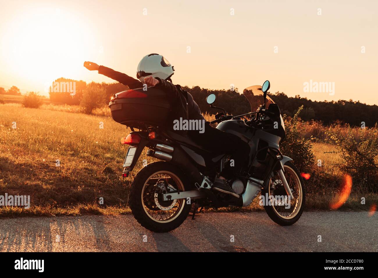 Female biker sitting on her bike, relaxing. Afternoon light, copy space Stock Photo