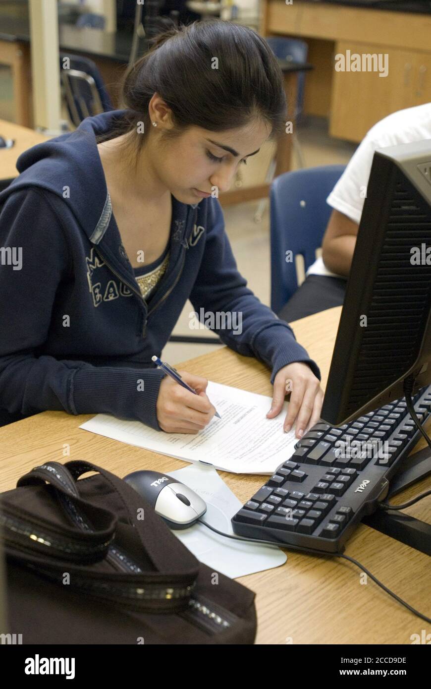 Texas: Hispanic 10th-grade female student writes on paper in high school computer lab. ©Marjorie Cotera /Daemmrich Photos Stock Photo