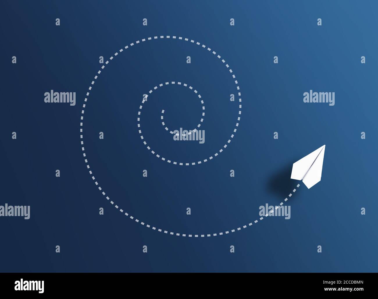 top view of paper plane flying spiral path against blue background, going around in circles concept Stock Photo