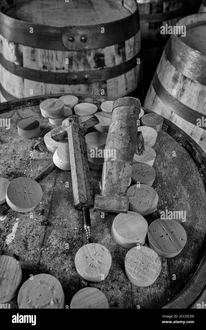 Tools to insert and remove bungs from whisky barrels, on the top  of a dusty old whisky barrel, black and white image Stock Photo