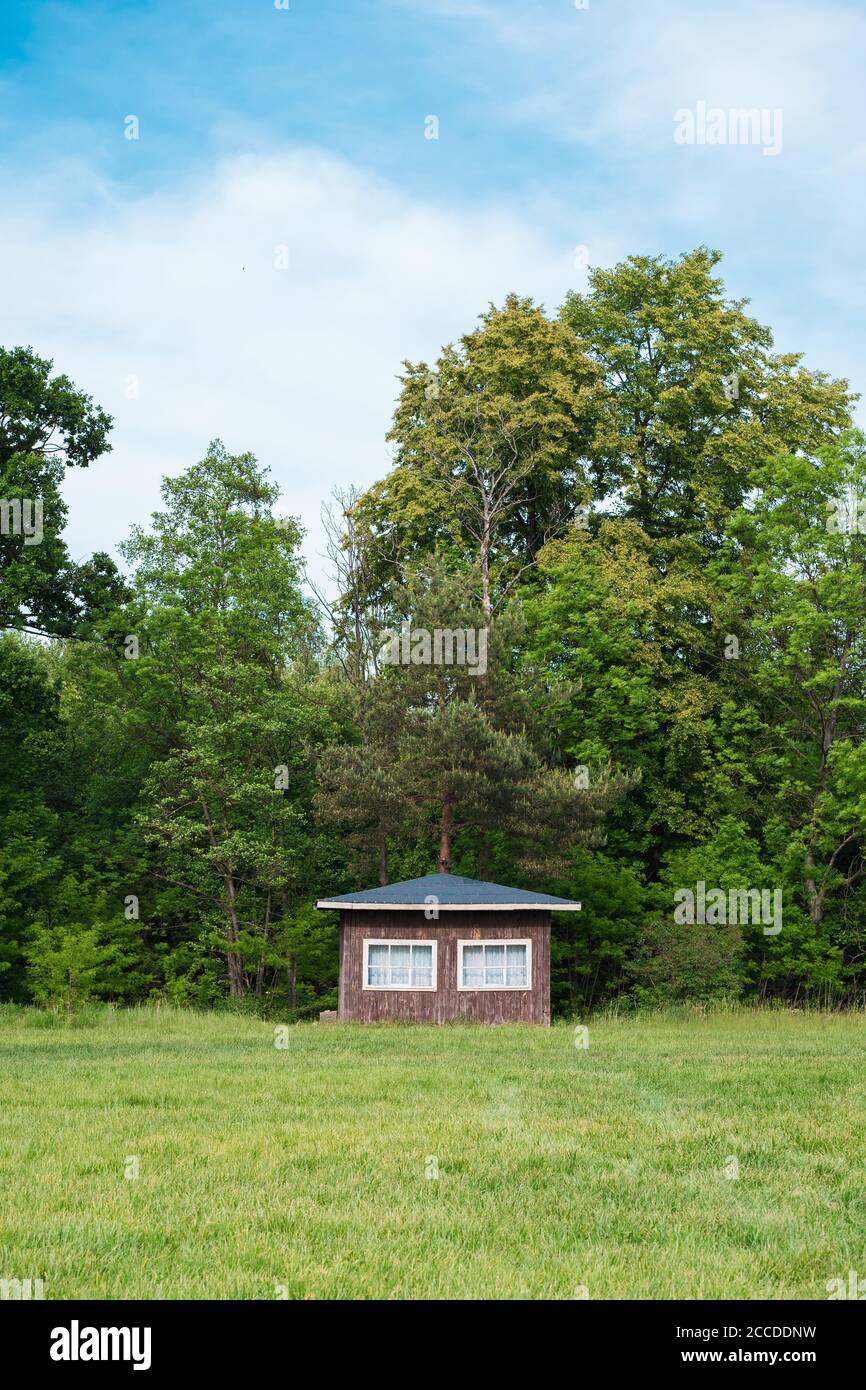 Traditional small wooden scandinavian house at the forest edge. Typical summer cottage. Countryside authentic cozy little cabin in a rural area Stock Photo