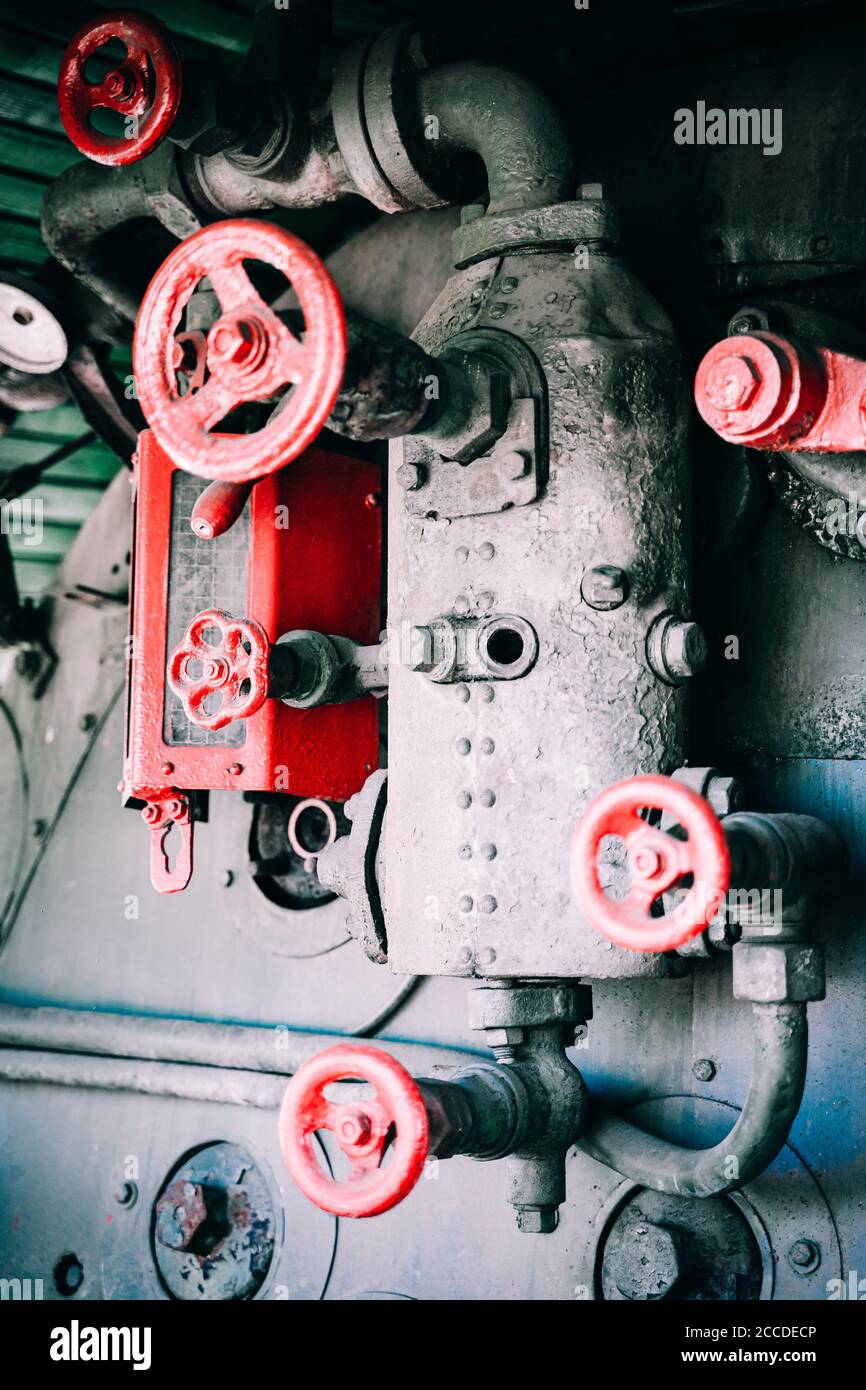 Huge vintage steam locomotive interior, black and red painted steel train. Coal-powered steam express on tracks. Inside view of power parts of machine Stock Photo