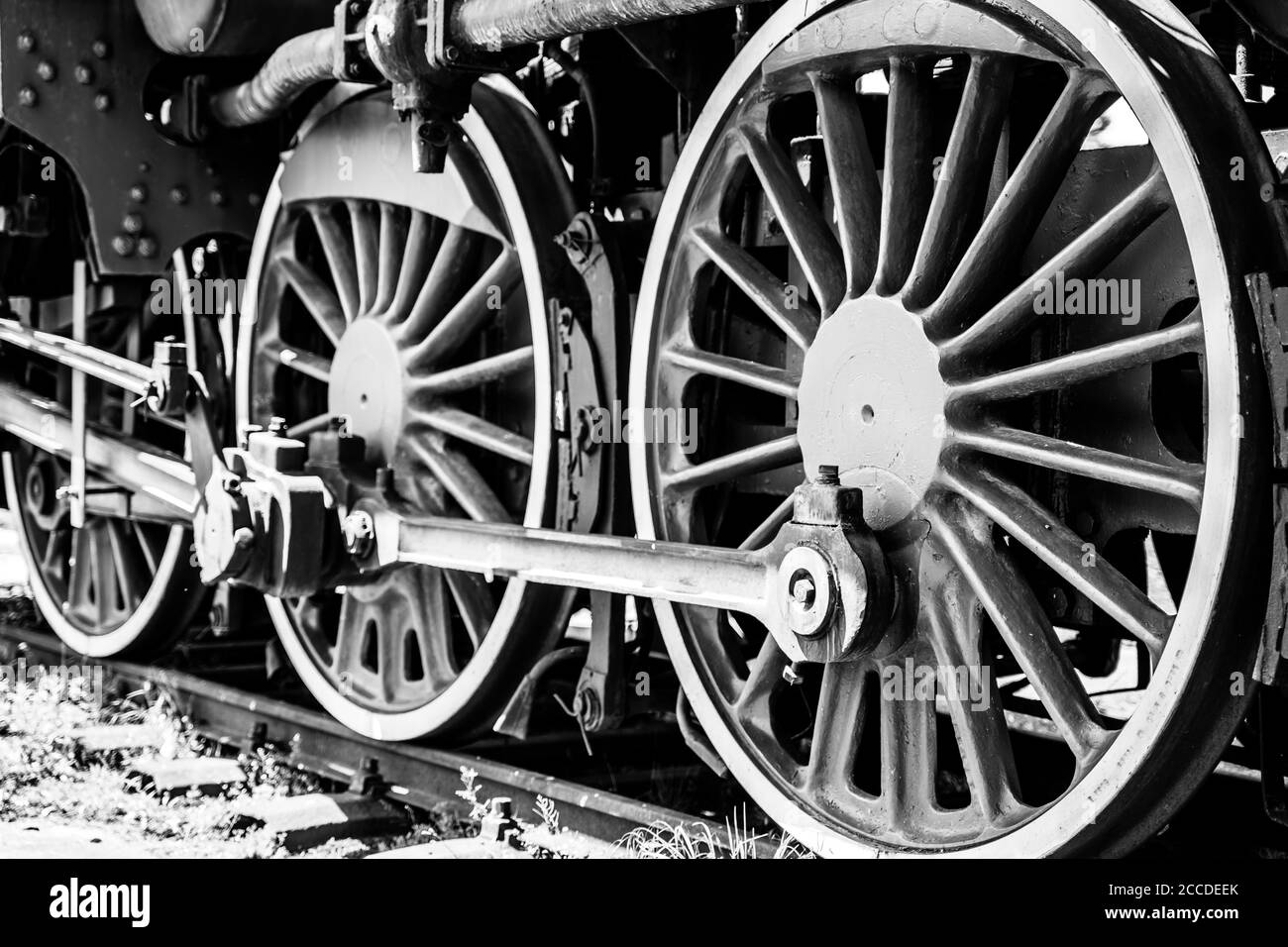 Huge vintage steam locomotive, red painted steel wheel detail close up. Coal-powered steam train on a siding. Classic gigantic heavy railway machinery Stock Photo