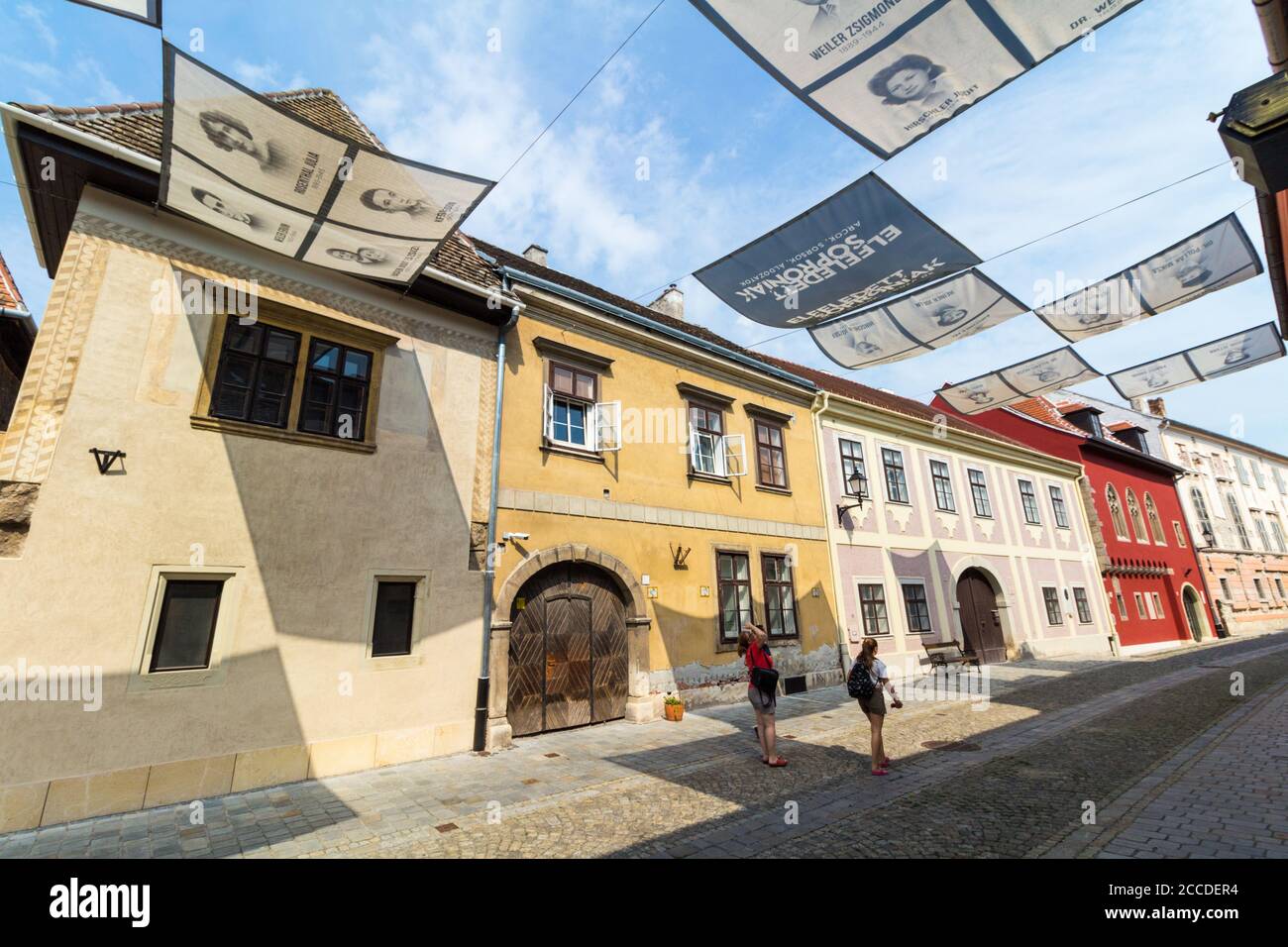 Uj utca (New Street) with images of Jewish victims of Holocaust over the street, Sopron, Hungary Stock Photo