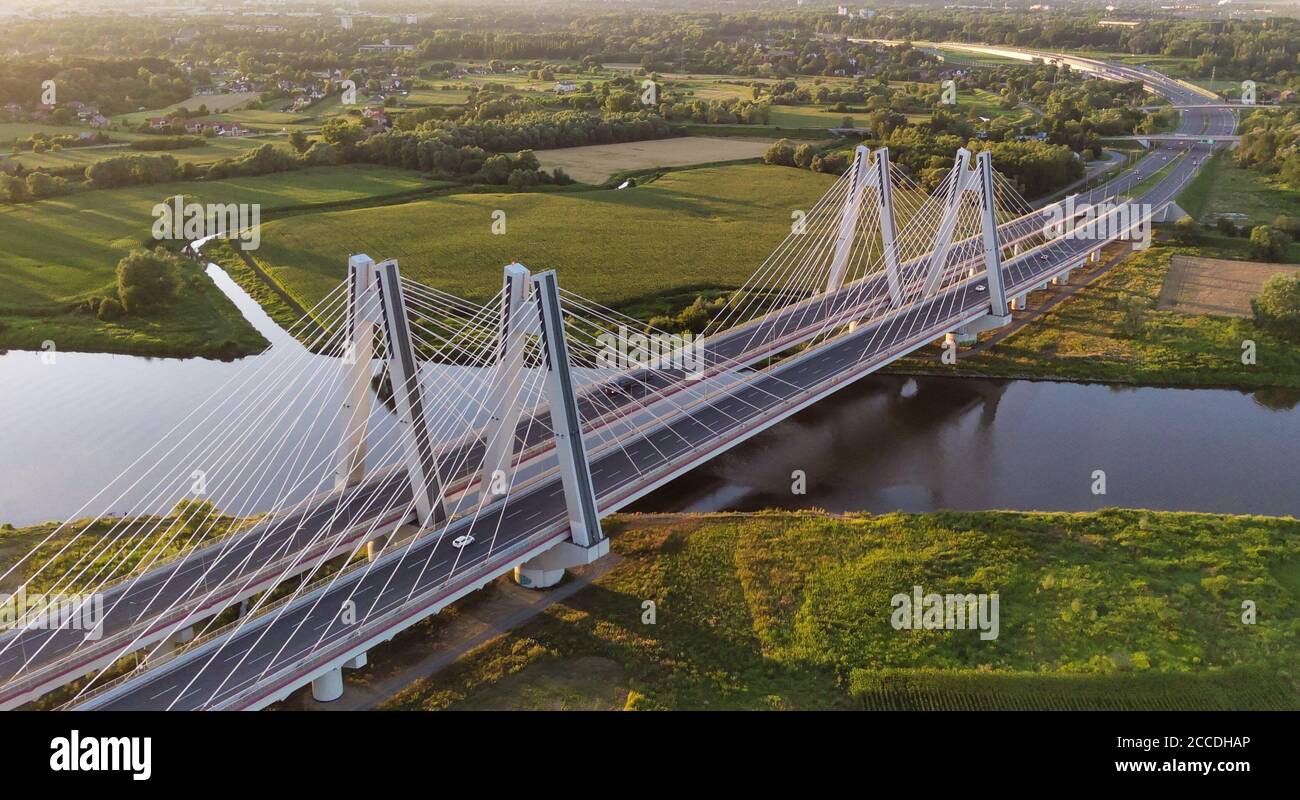 Monumental, lighted, modern double cable-stayed bridge over Vistula River in Krakow, Poland during sunset. Concrete and steel industrial construction Stock Photo