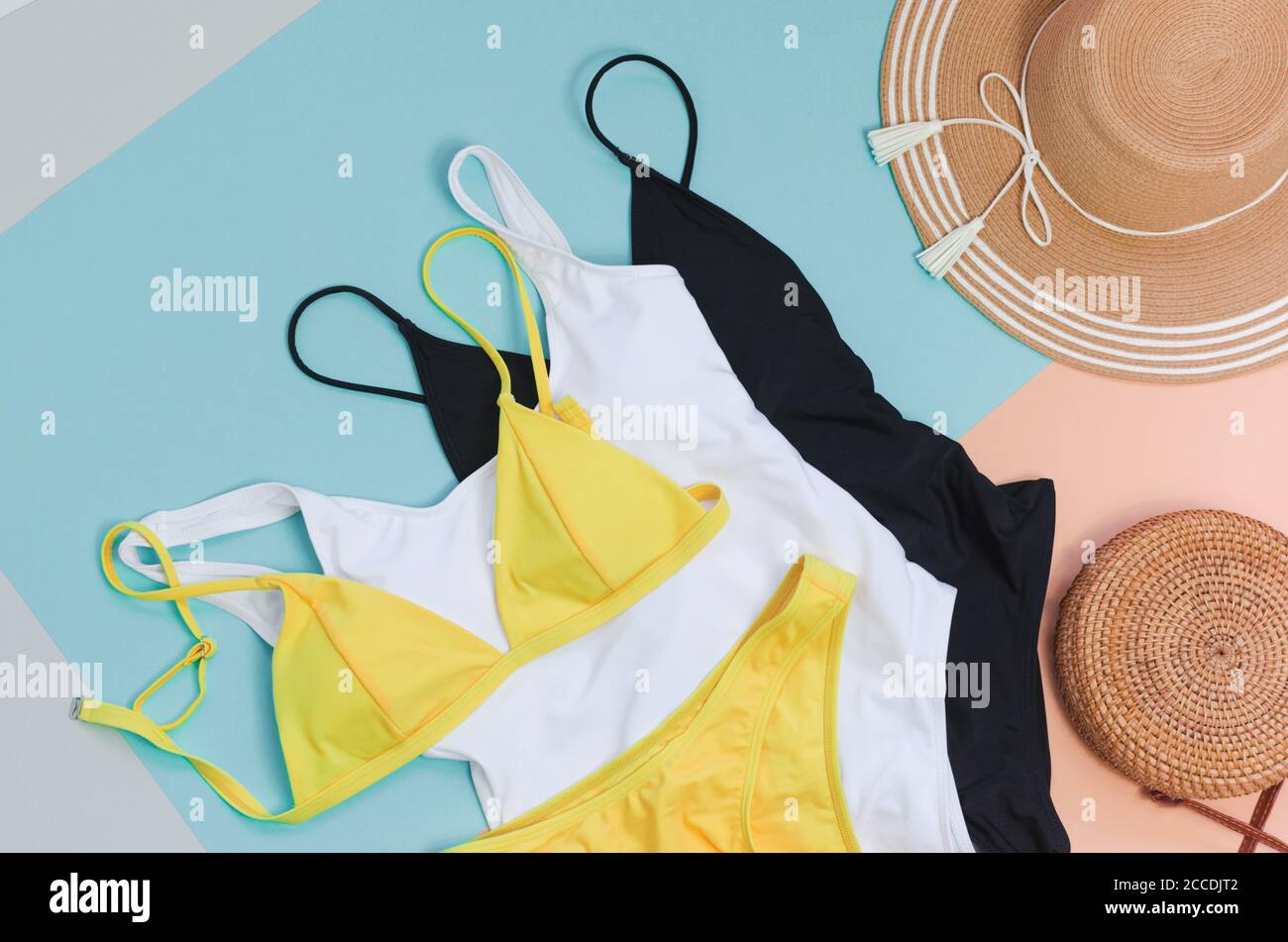 Three swimming suits with bag and straw hat for summer. Flatlay Stock Photo