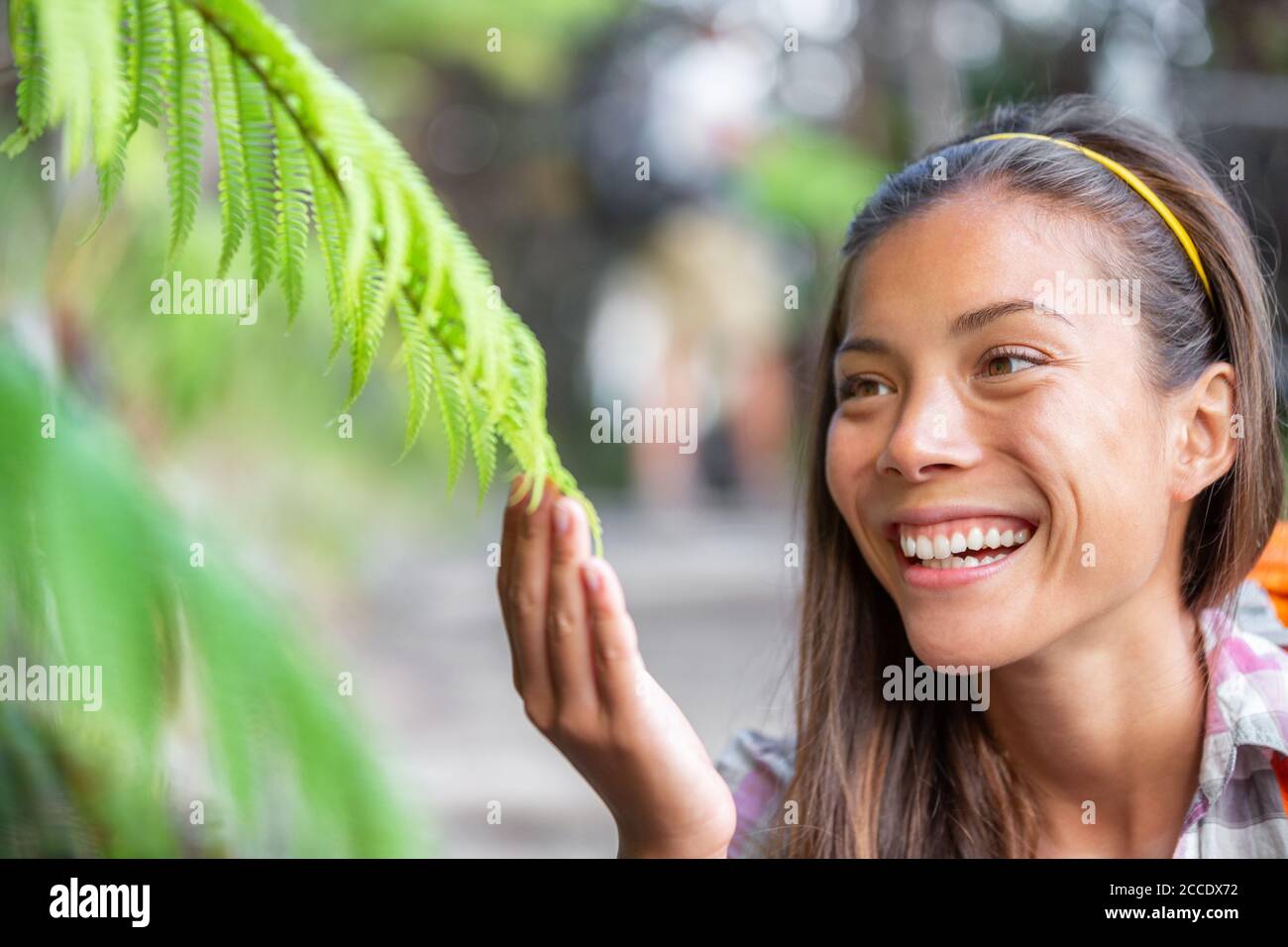 Nature interpretation park guide woman touching plants for environment class about wilderness in forest. Asian naturalist teaching plants biology Stock Photo