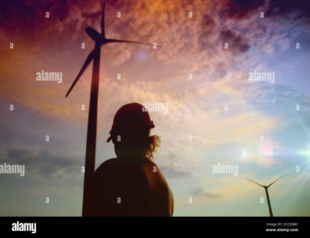 Engineer in a wind turbine. A woman in a helmet supervises the operation of the electric windmills. Ecology and renewable energy sources concept. Stock Photo