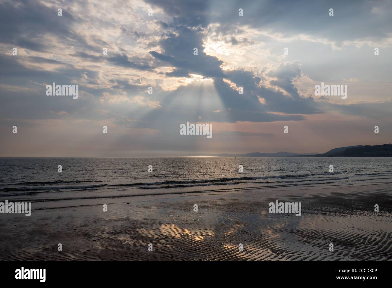 Dramatic sky with sun rays above Colwyn bay, North Wales. Dawn sunrise on the coast with a calm sea Stock Photo