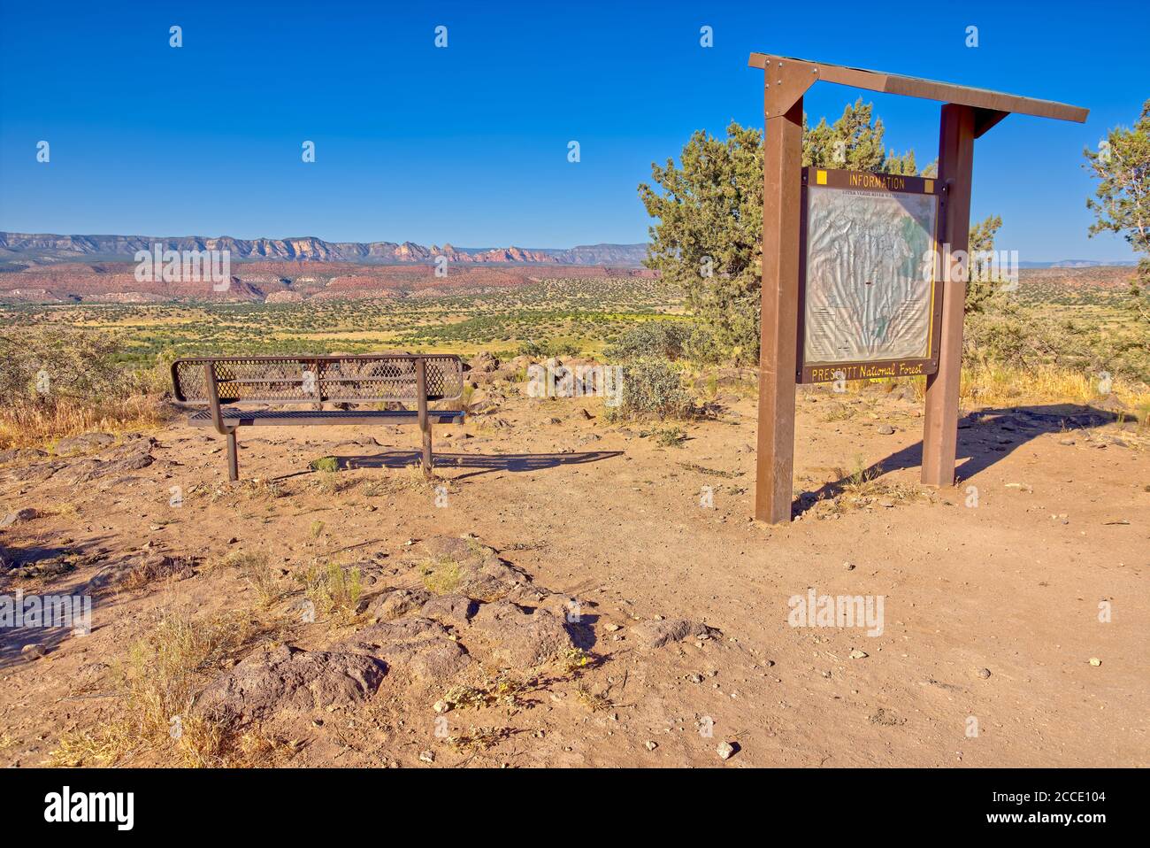 An overlook sitting bench with information sign for the Upper Verde River Watershed near Perkinsville Arizona. The red rocks in the distance is the Sy Stock Photo