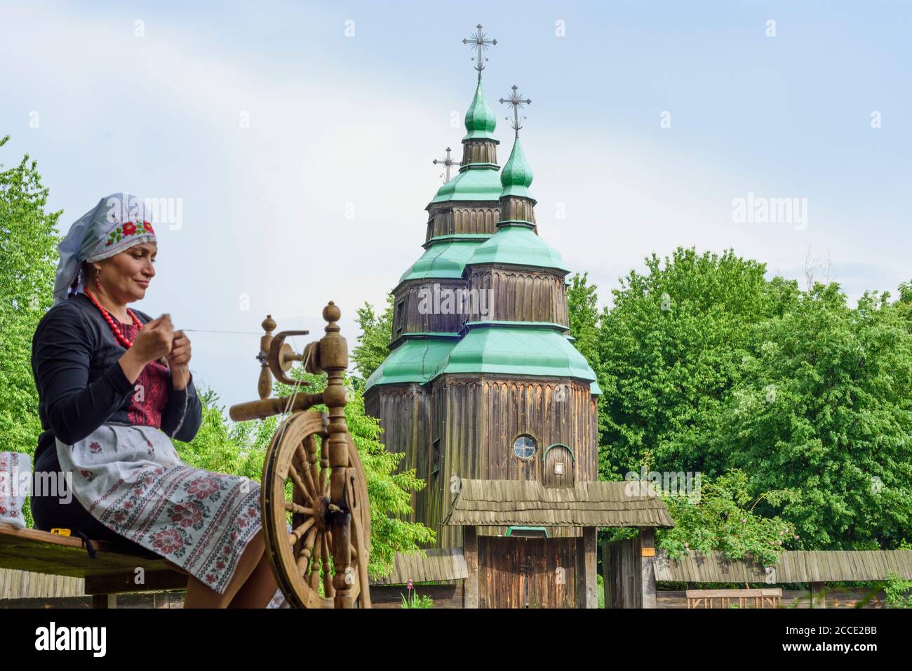 Kiev (Kyiv), Museum of Folk Architecture and Folkways of Ukraine in Pyrohiv, Zarubincy village church, wooden church, woman at spinning wheel in Kyiv, Stock Photo