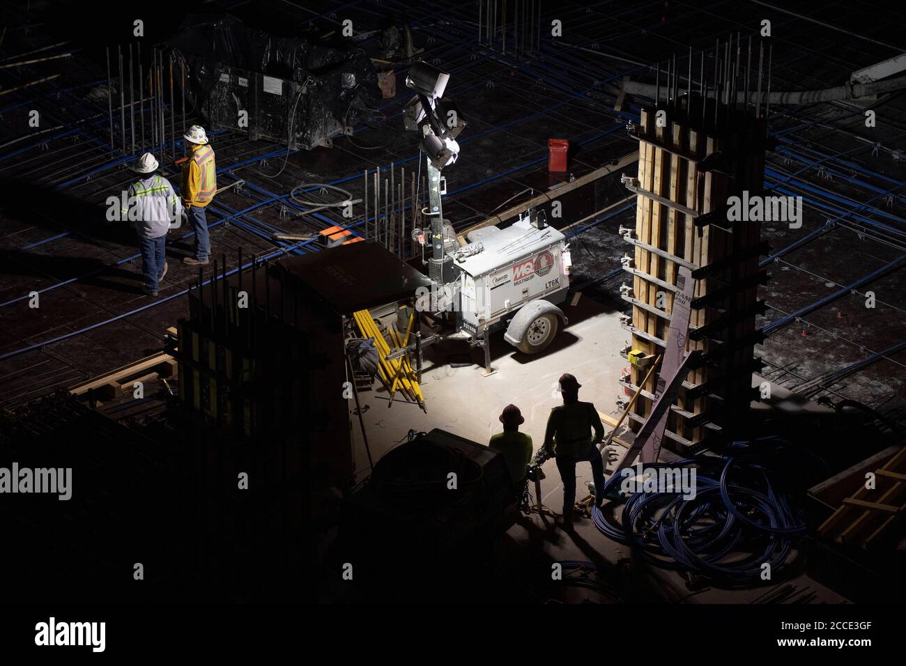 Austin, TX USA July 25, 2020: A generator-powered spotlight shines on concrete crews working on the parking garage of a 53-story building during a night-time pour in downtown Austin, TX. Huge construction projects continue unabated in Texas despite the nationwide COVID-19 pandemic and the state stricken with over a half million cases and 10,000-plus deaths. Stock Photo