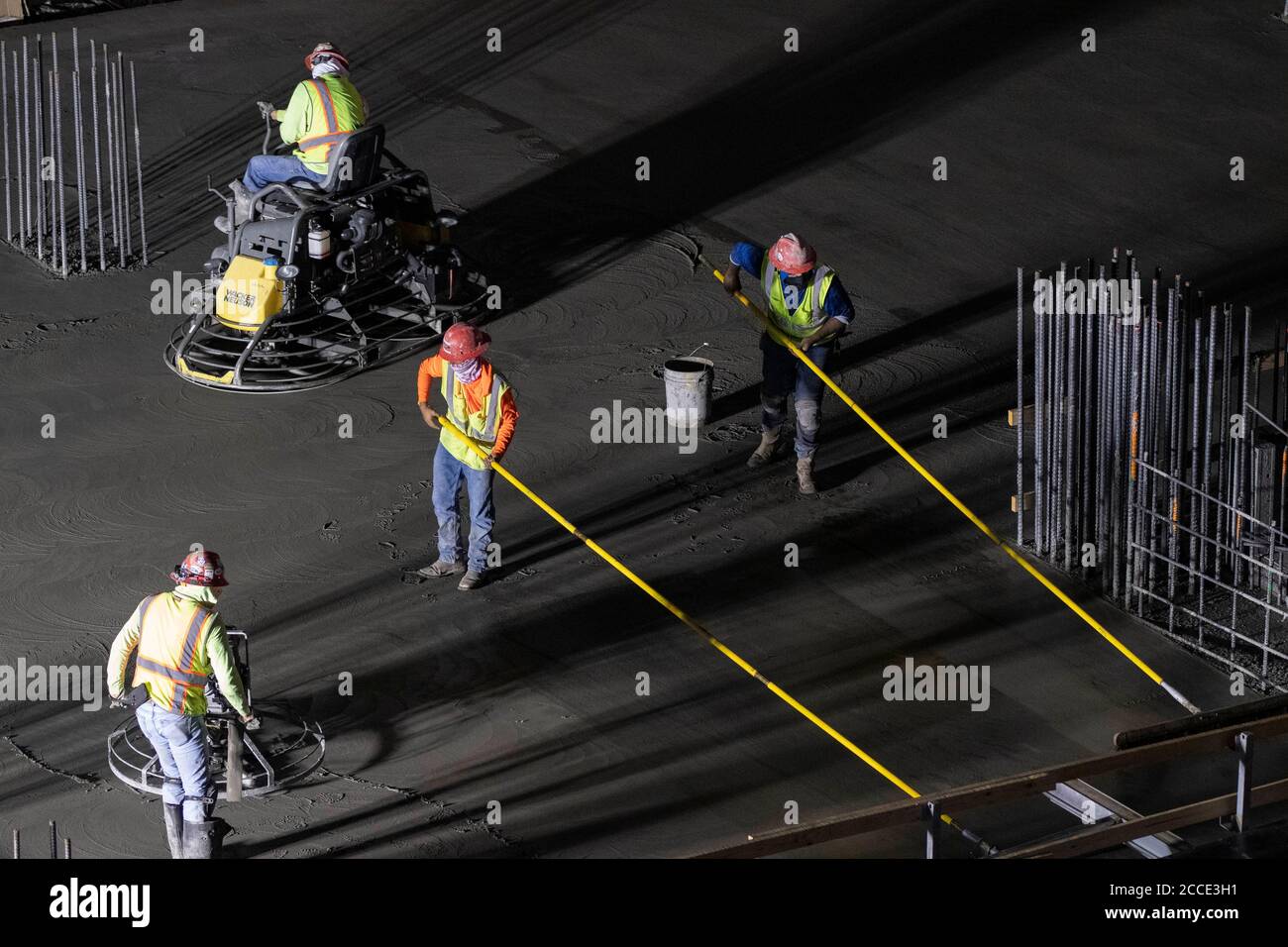 Austin, TX USA July 25, 2020 Concrete workers use longhandled screeds