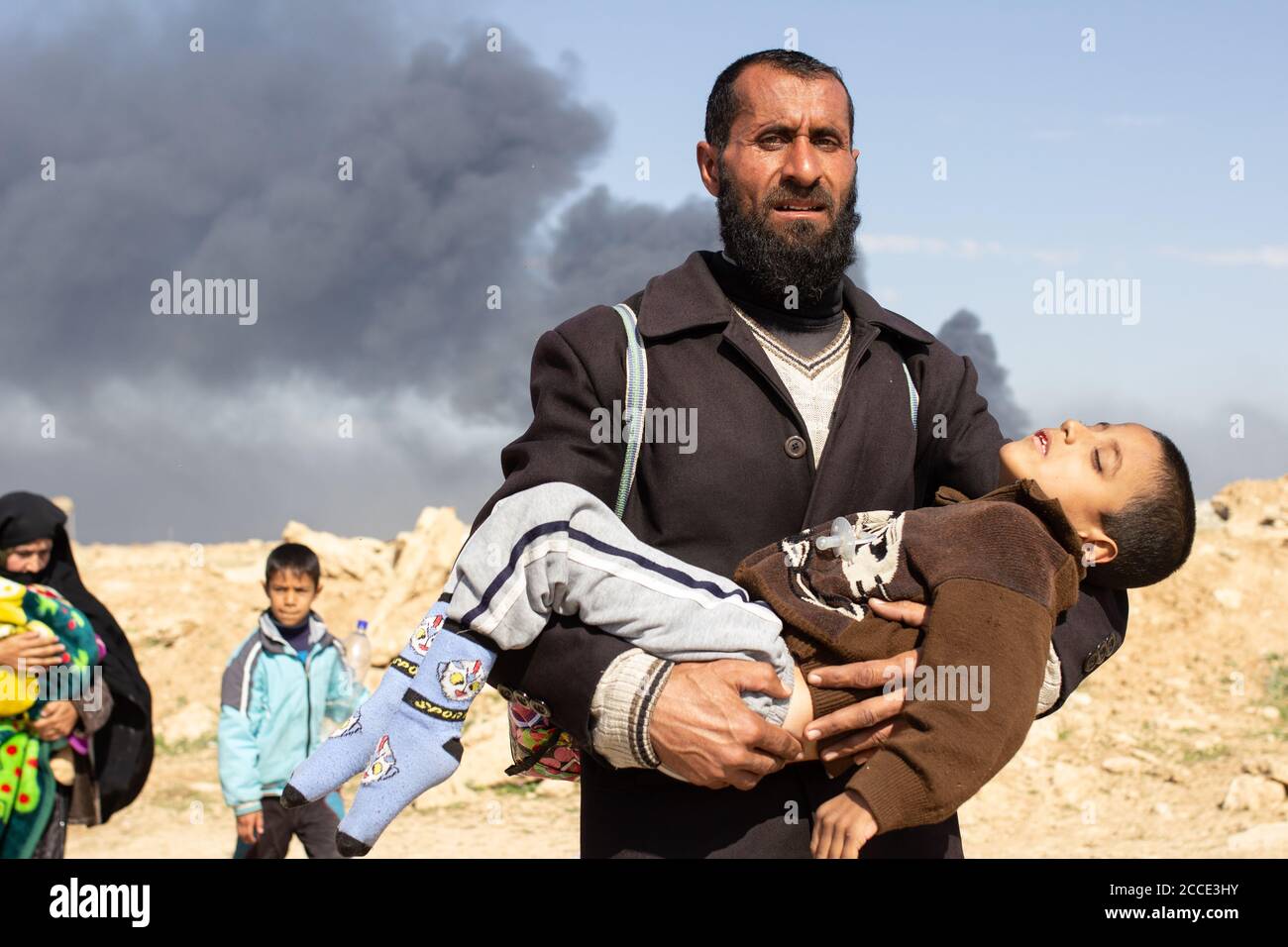 Mosul, Iraq. 7th Mar 2017 A man carries an exhausted young boy to a refugee gathering point near Tall ar Rayyan neighborhood in West Mosul. Credit: Young G. Kim Stock Photo