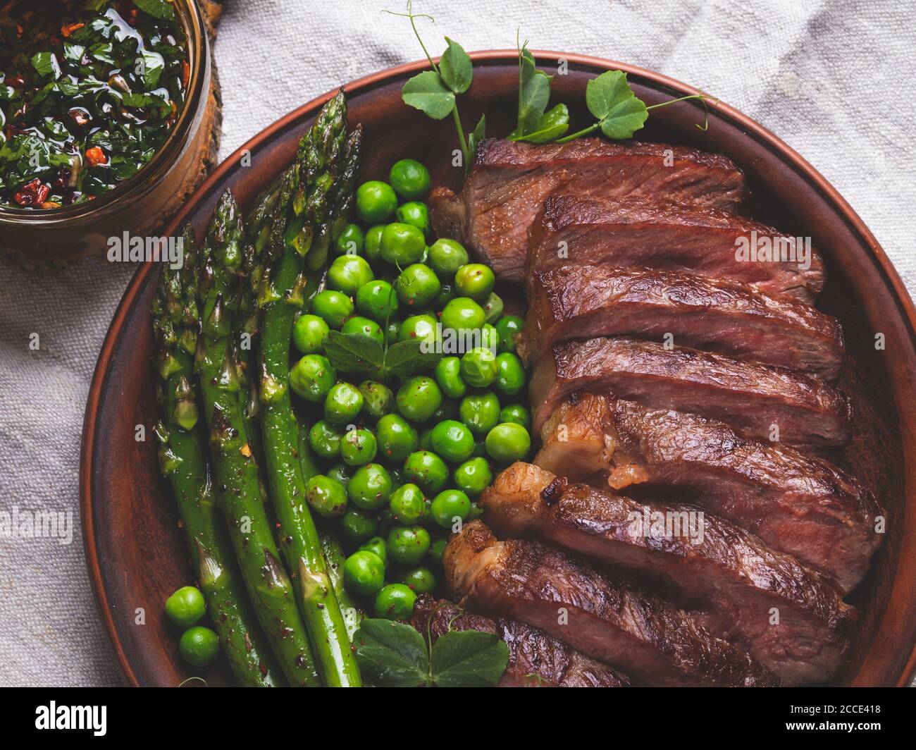 juicy roasted beef sliced steak, with green peas, roasted asparagus, on plate Stock Photo