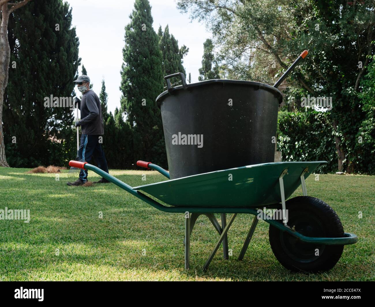 Iron wheelbarrow carrying bucket of grass cut from a garden Stock Photo