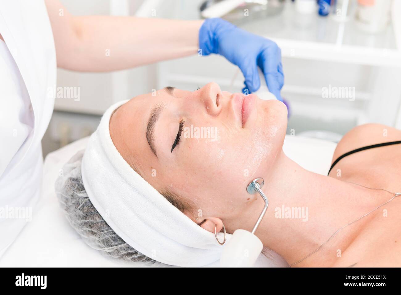 The young female client of cosmetic salon having microcurrent procedure on her face with special devices, close-up. Beautician using electrical impuls Stock Photo