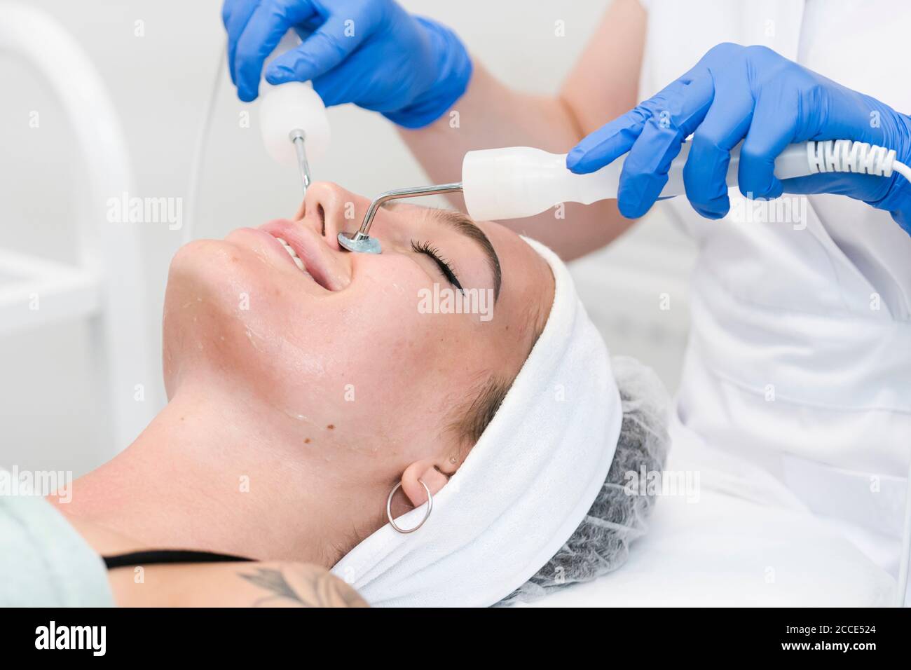 The young female client of cosmetic salon having microcurrent procedure on her face with special devices, close-up. Beautician using electrical impuls Stock Photo