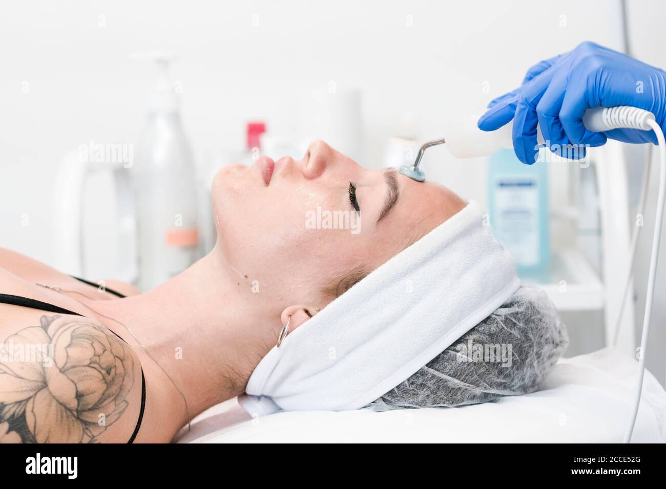 The young female client of cosmetic salon having microcurrent procedure on her face with special devices, close-up. Beautician using electrical impuls Stock Photo