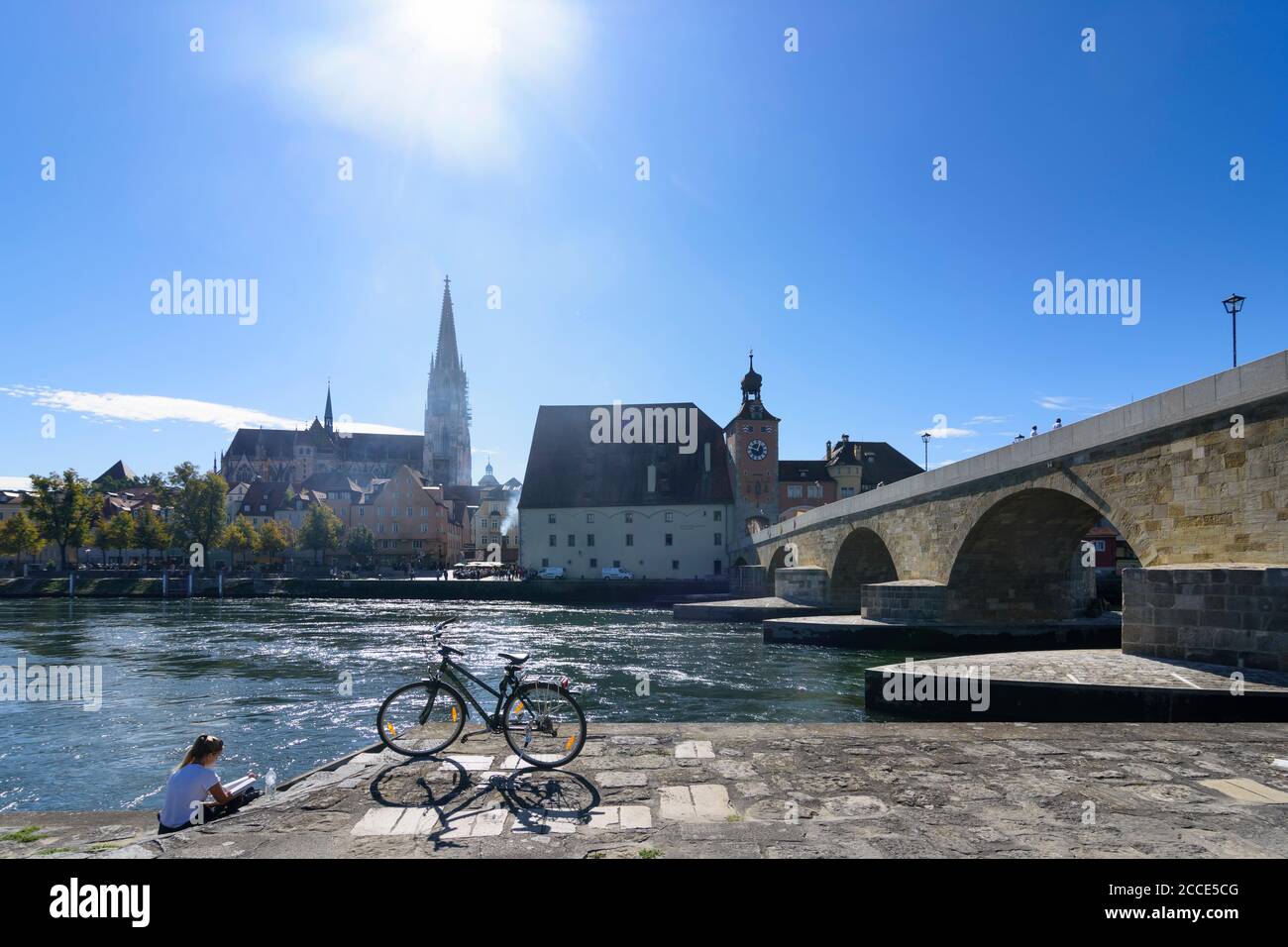 Regensburg, river Donau (Danube), Steinerne Brücke (Stone Bridge), St. Peter's Church, the Regensburg Cathedral, girl reading in Upper Palatinate, Bav Stock Photo